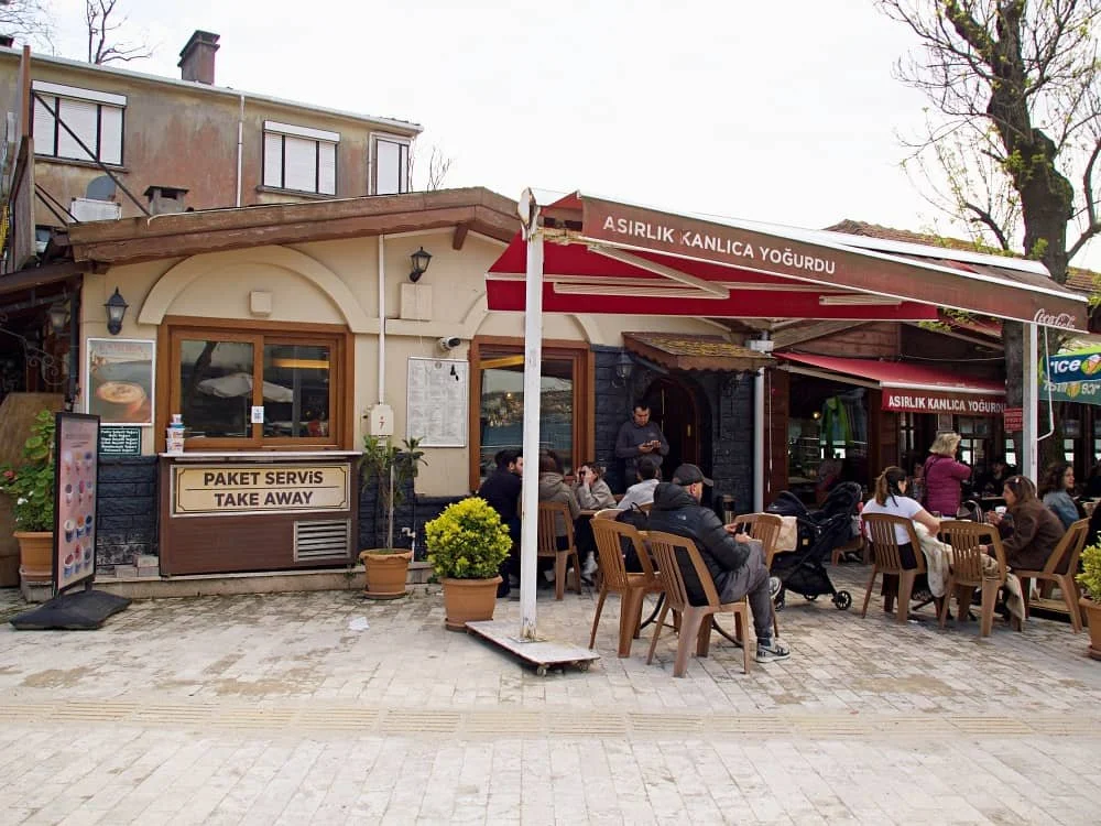 The outside of asirlik kanlica yogurt cafe with people sitting outside and a small area for takeaway orders