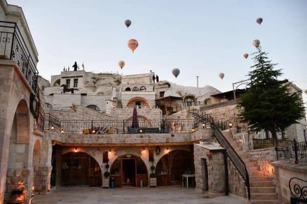 Hot air balloons float over Zen Cappadocia House at sunrise, best hotel in cappadocia with view