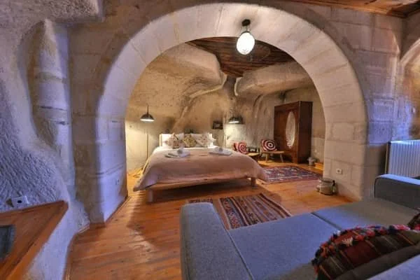 A spacious cave room with double bed, a sofa and Turkish rugs at Potamia Cave Suites, best view cave hotels in cappadocia
