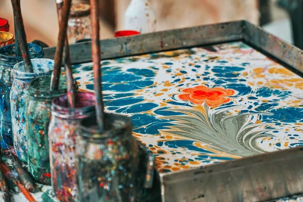 A close up of a tray of water with a flowered pattern on it in an ebru class