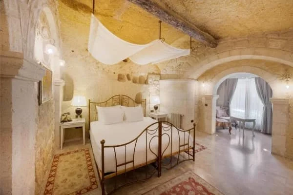 A wrought iron luxurious double bed and a seating area with drapes on the windows at Tafoni Houses Cave Hotel, best 5 star hotel in cappadocia