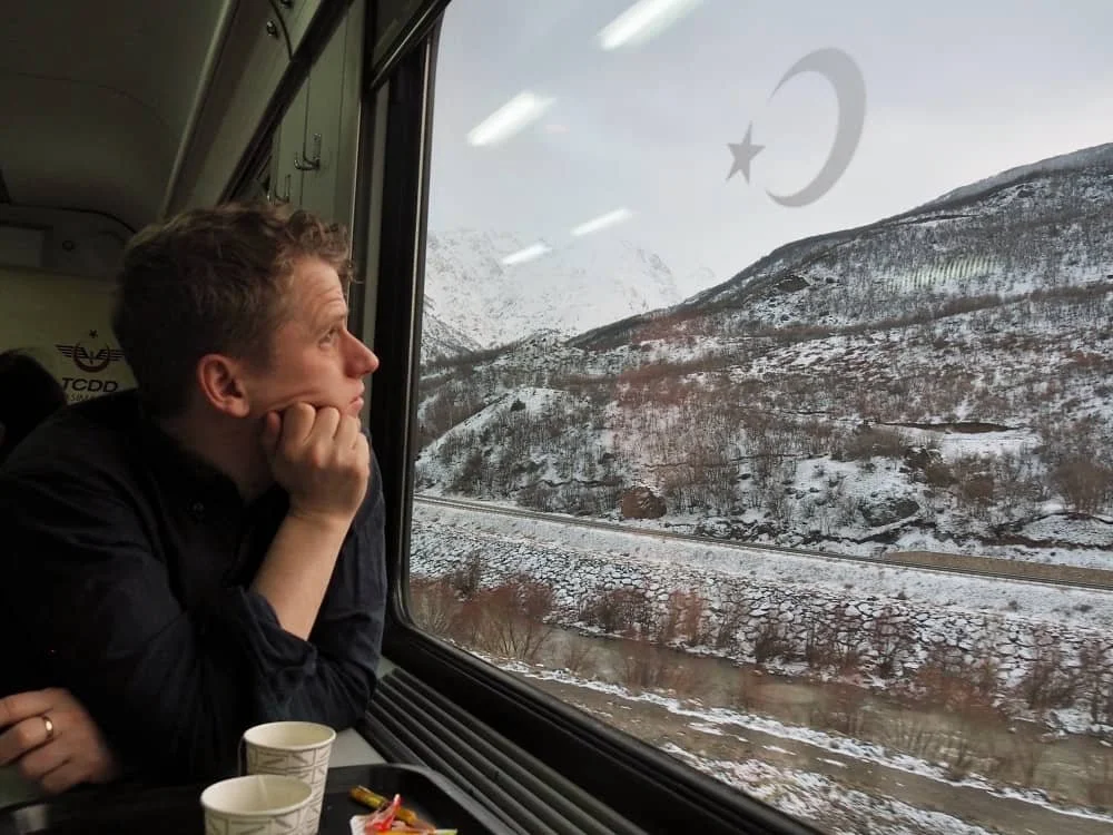 A man looking out of the window at the scenery in the dining car of the Eastern Express, train from ankara to kars