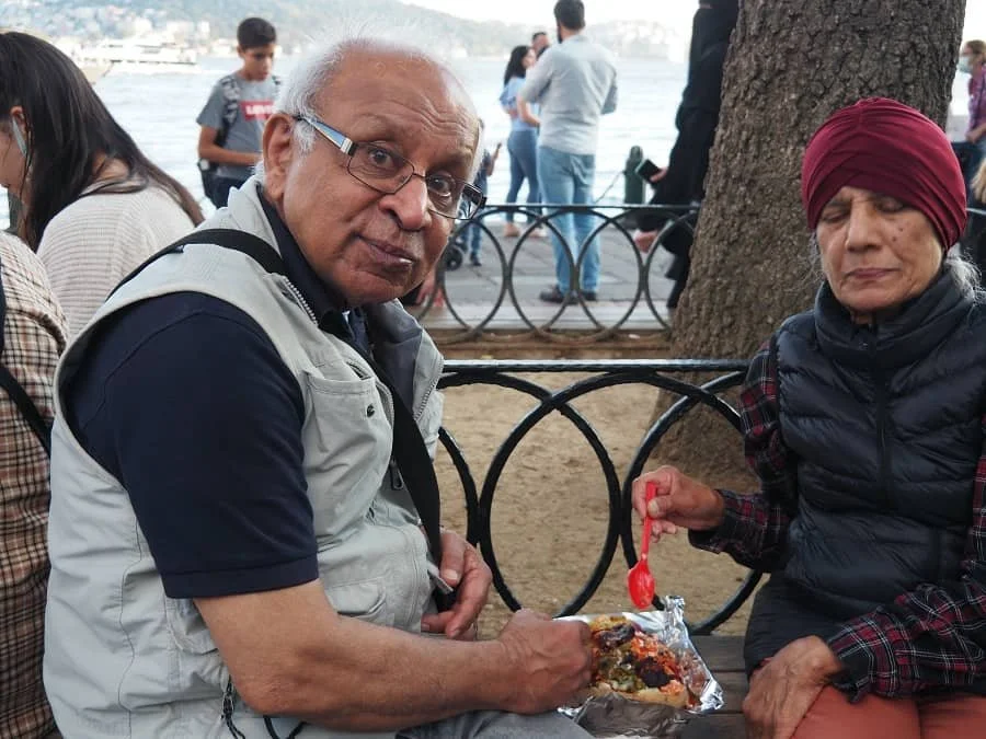 Sasha's dad smiles at the camera while tucking into kumpir (baked potato with various fillings) in Ortakoy in Istanbul