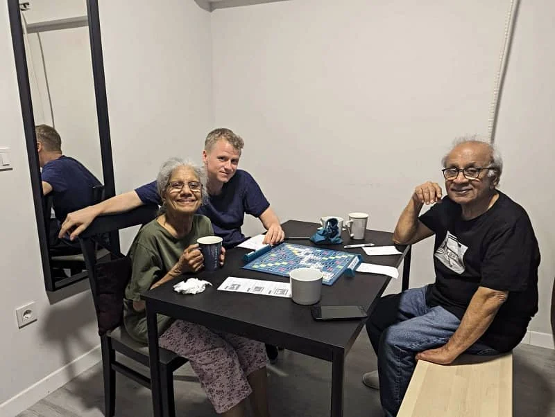 Vincent, Sasha's mum and dad sit around a table playing Scrabble in Istanbul