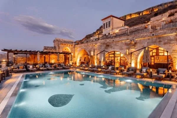 The stunning outdoor swimming pool in the early evening lit up with golden lights at Kayakapi Premimum Caves Hotel, best resorts in cappadocia