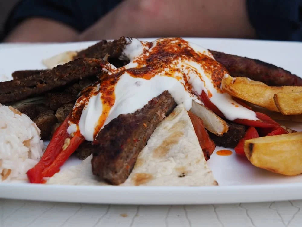 close up of a kebab topped with a traditional yogurt and chilli butter sauce