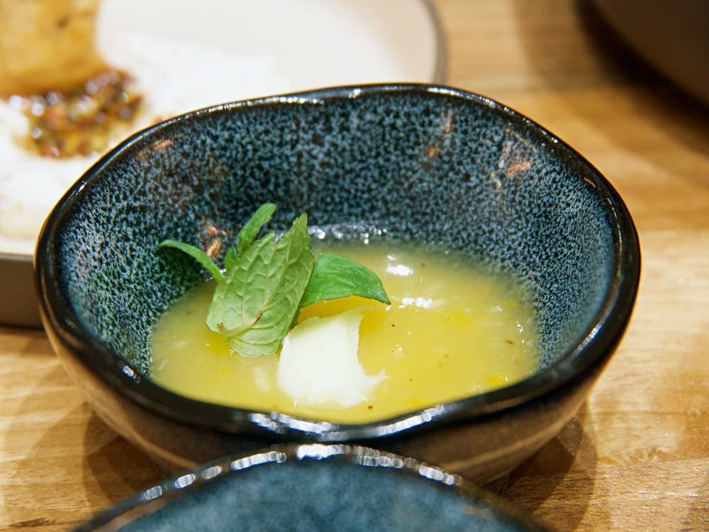 Close up of a speckled blue dish filled with limontella, Limon Galata's signature spread, topped with clotted cream and a sprig of mint