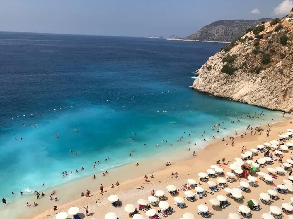14 day travel itinerary turkey People swimming in the aquamarine waters or walking along the white sand beach at KaputaĆ beach in KaĆ in TĂŒrkiye
