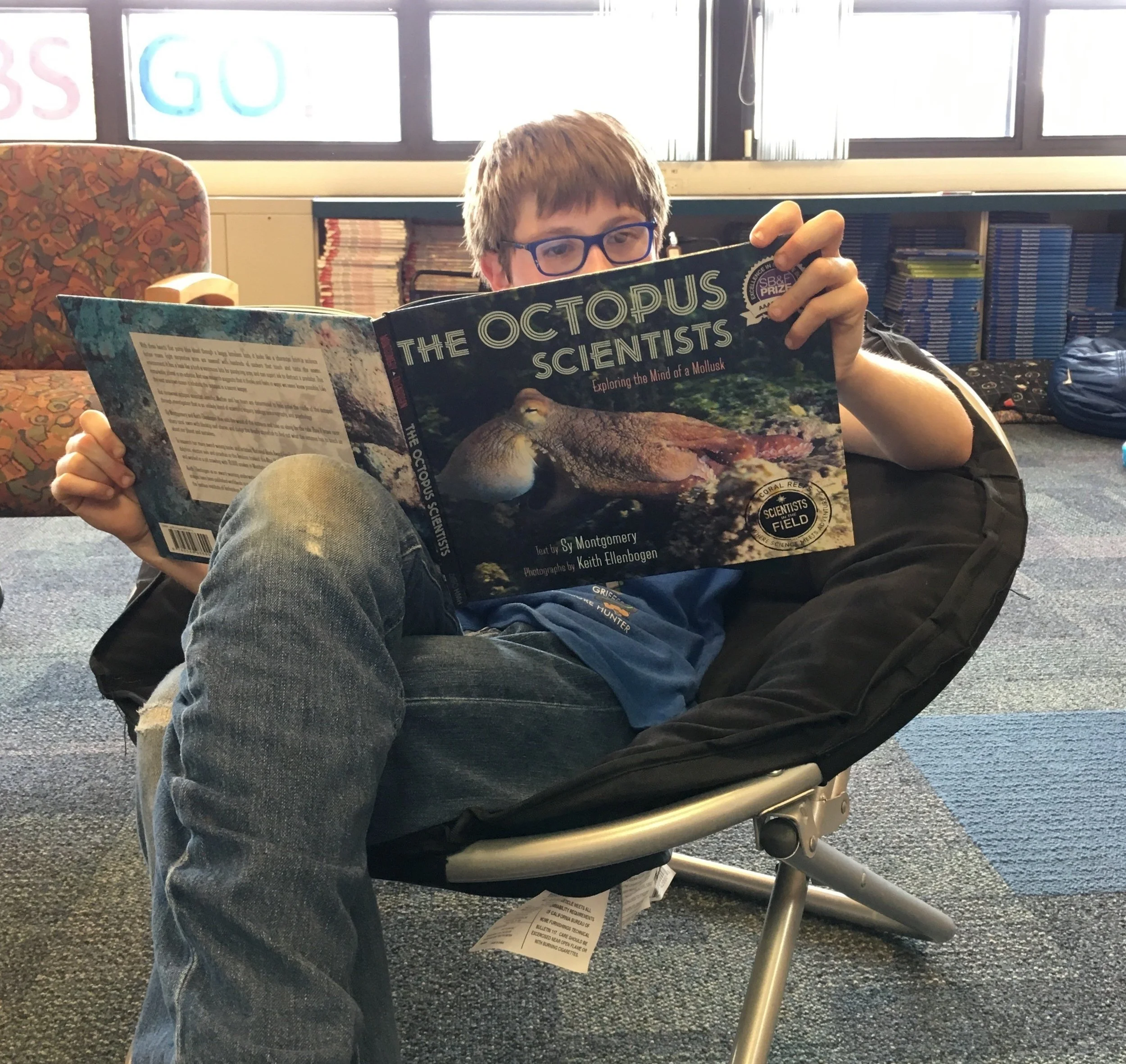 A student at Oliver McCracken Middle School enjoys The Octopus Scientists, Exploring the Mind of a Mollusk , donated by Evanston Subaru in 2016. Photo used with permission.