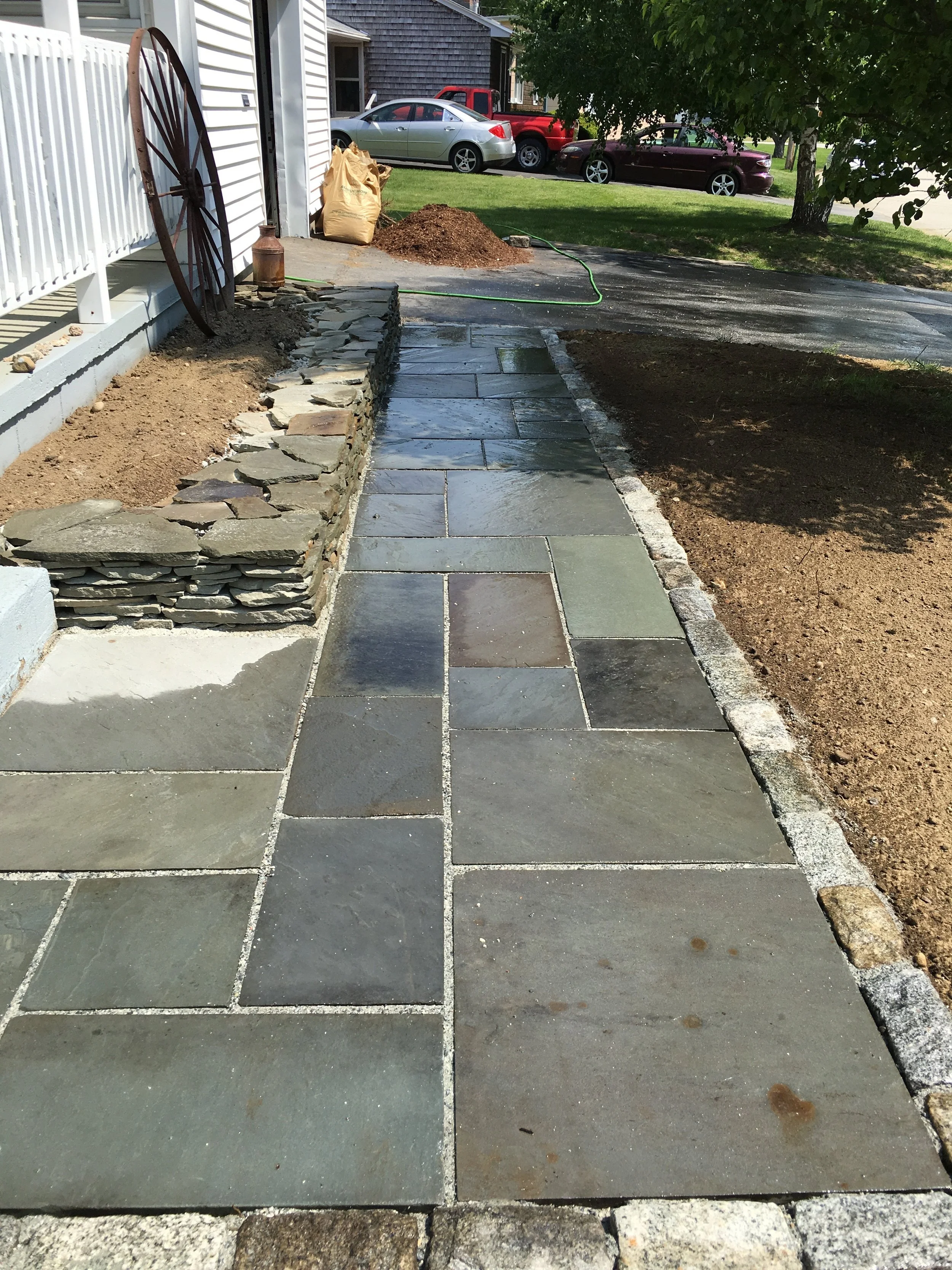Patterned blue stone with cobblestone edging and flatstone wall.