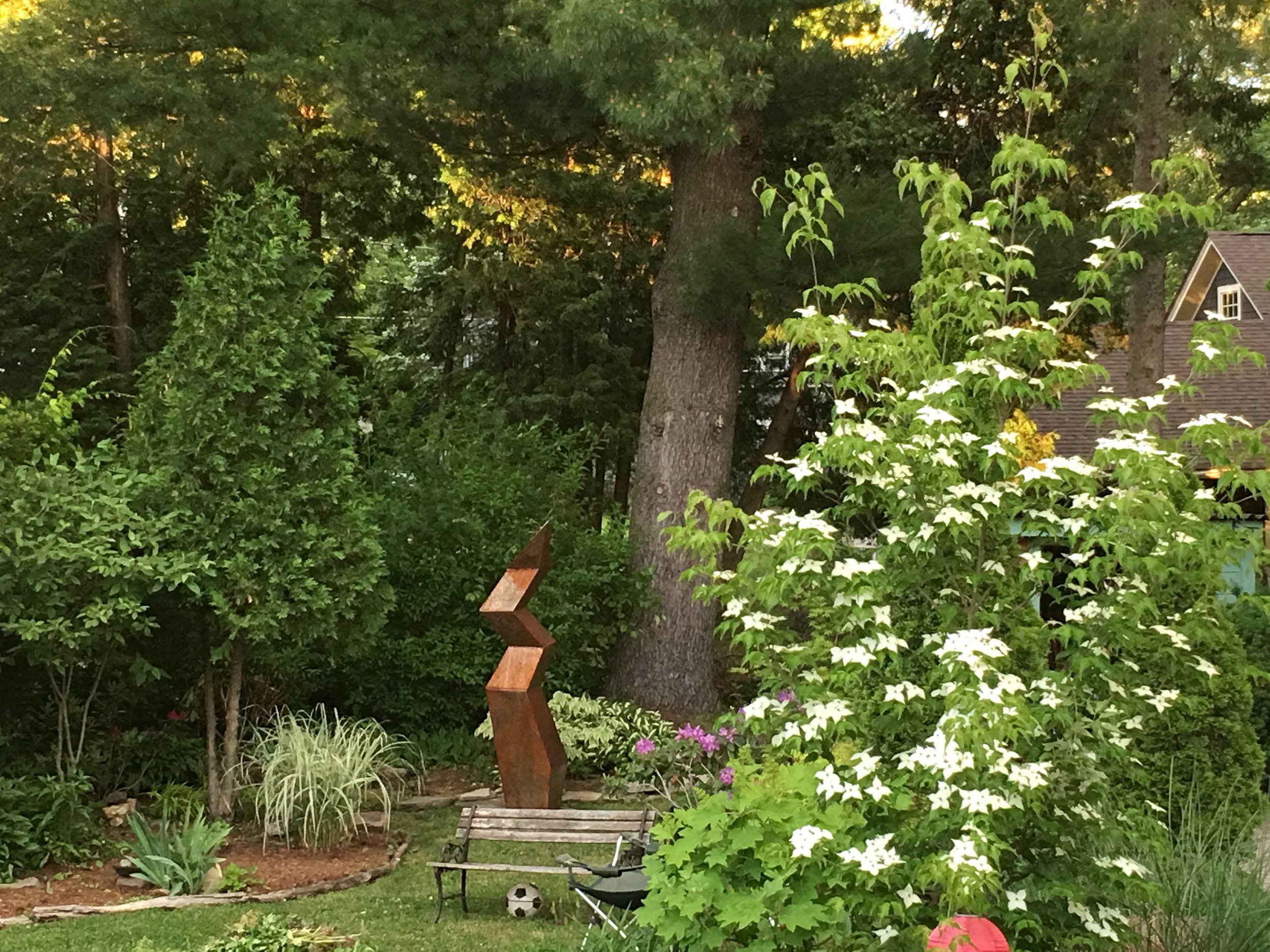 Lovely mixed textures in the garden accentuated by steel sculpture and charming park bench to welcome you in.