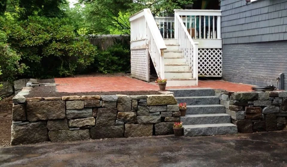 Granite and fieldstone wall, granite steps and raised brick patio...