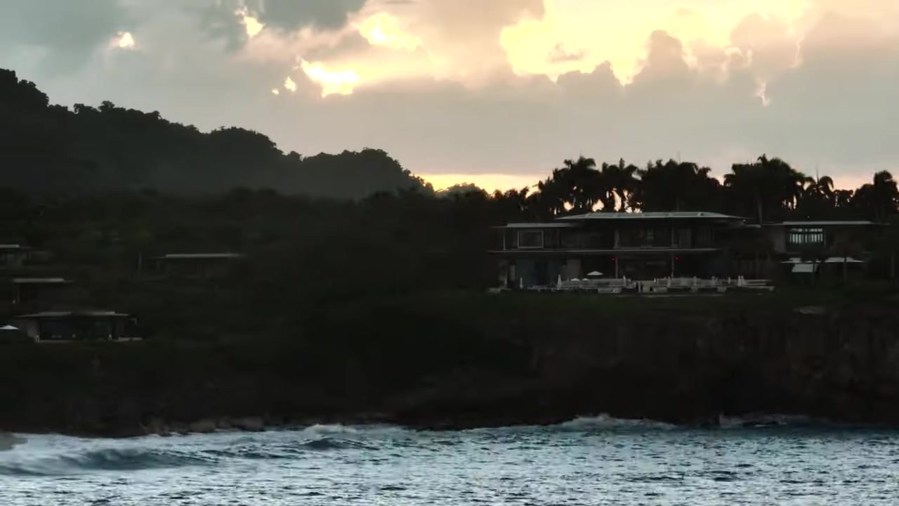 Amanera at sunset with the main building on the cliff and sun breaking through cloud