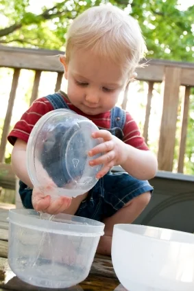 Boy playing with water in bowls; language activities at Canto Speech Therapy Online