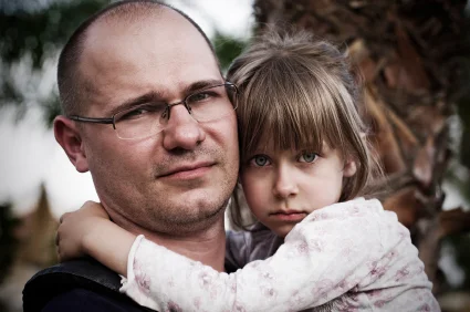 Worried dad holding girl with phonological speech disorder at Canto Speech Therapy Online