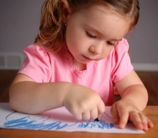 Little girl scribbling; early writing is a pre-reading skill. Learn more at Canto Speech Therapy Online
