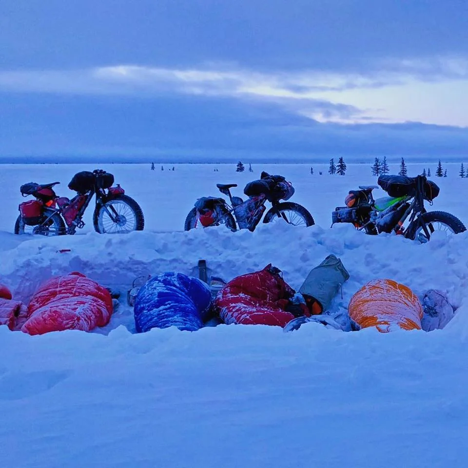 Enduring 5 snow fronts in less than two days that buried the trail in over a foot of snow and winds that would knock us off our feet, we made the group decision to make camp after breaking trail for 16 hours. We dug a hole big enough for the 4 of us and used our bicycles and the removed snow to create a wind break, creating a calm port in the storm to cook dinner and to sleep for a few hours. #iti2018 — with Craig Anthony Bullen and Adam Erritzøe .