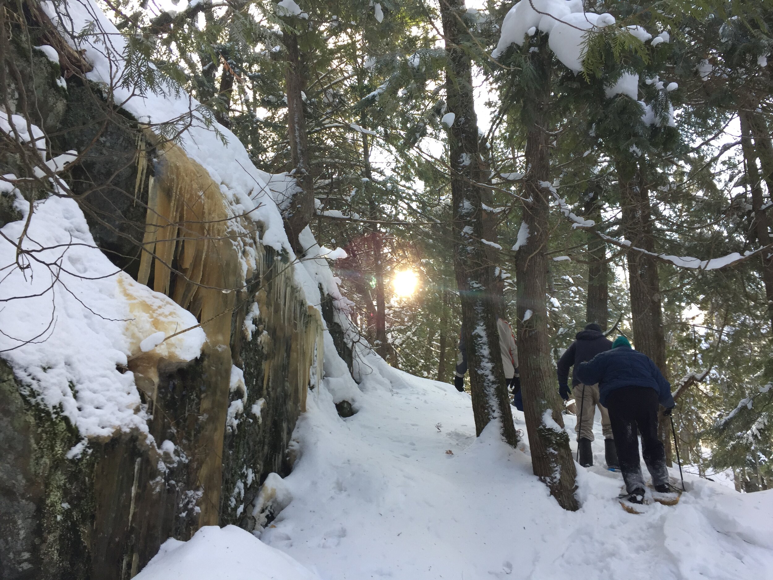 Snowshoers ascend around the outcrop