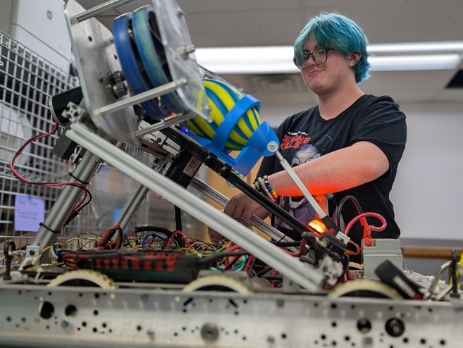 A high school FIRST Robotics student actively working on their robot