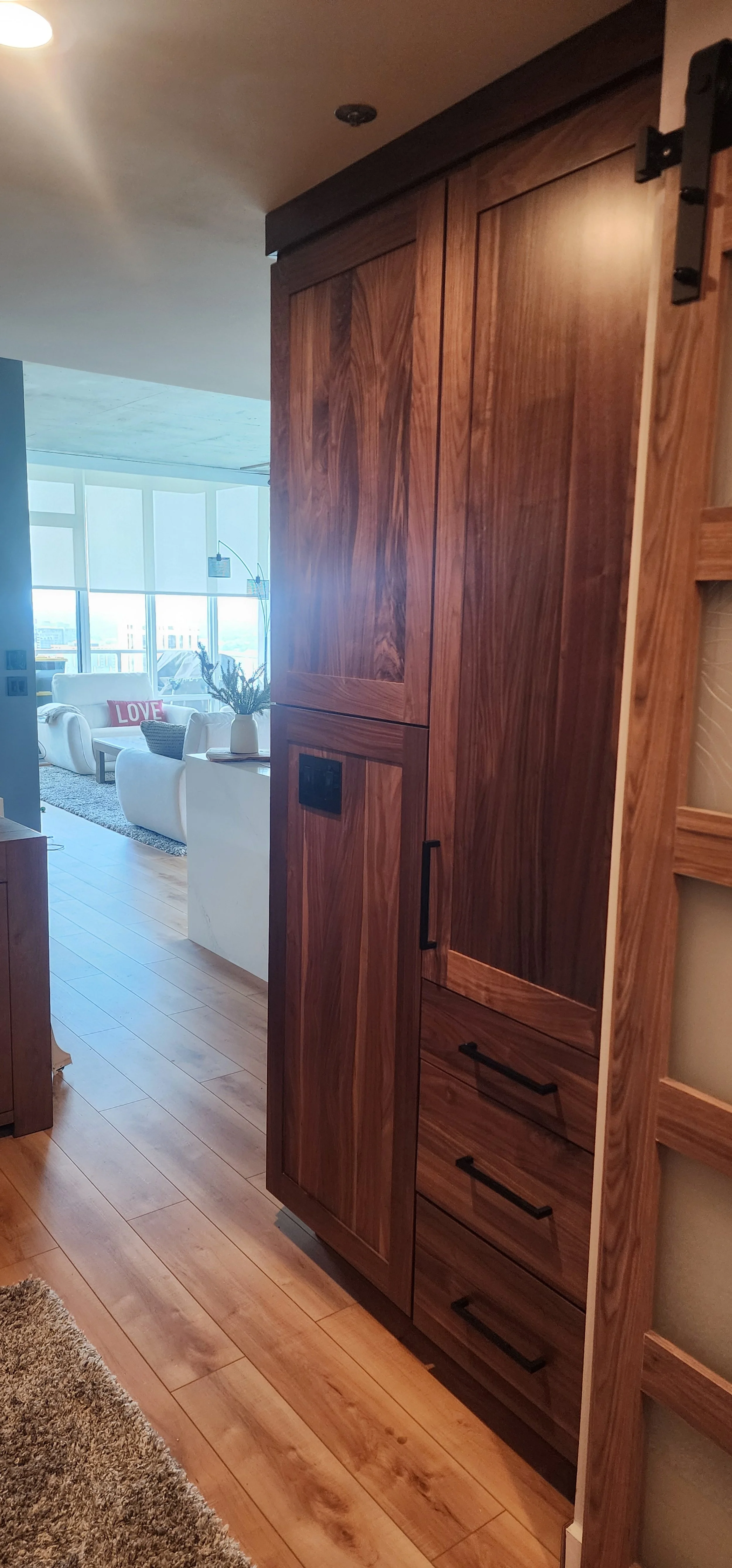 A tall walnut cabinet with black handles.