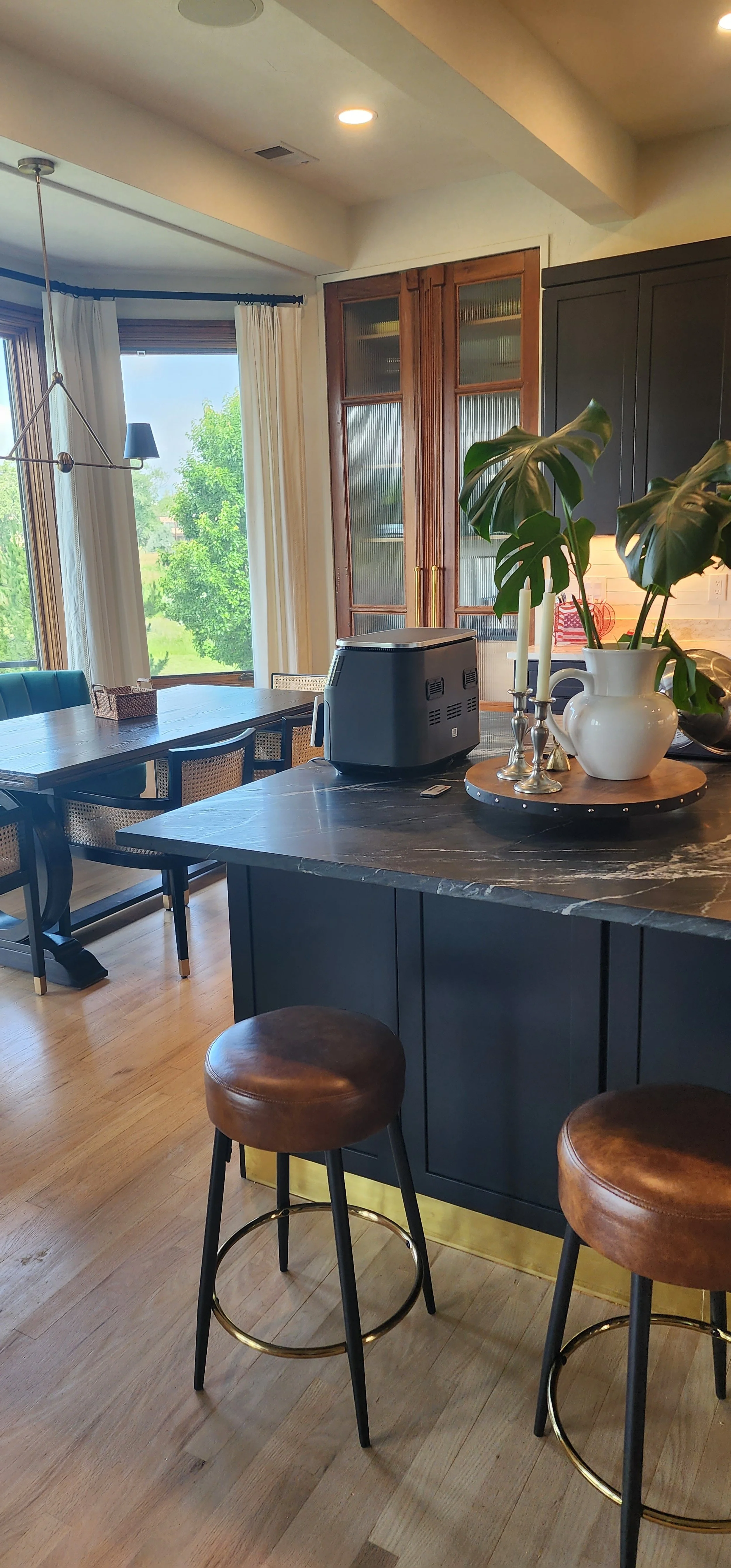 Kitchen and dining area with a large window, dining table, stools, and a kitchen island.