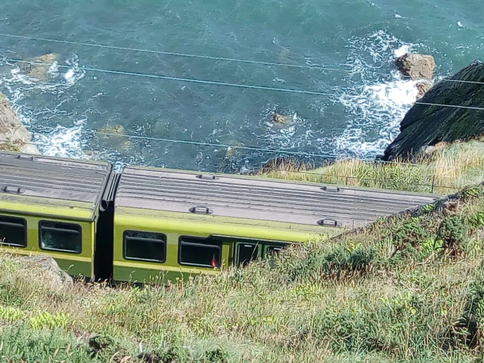 The DART electric train runs along the sea at the bottom of the cliffs.