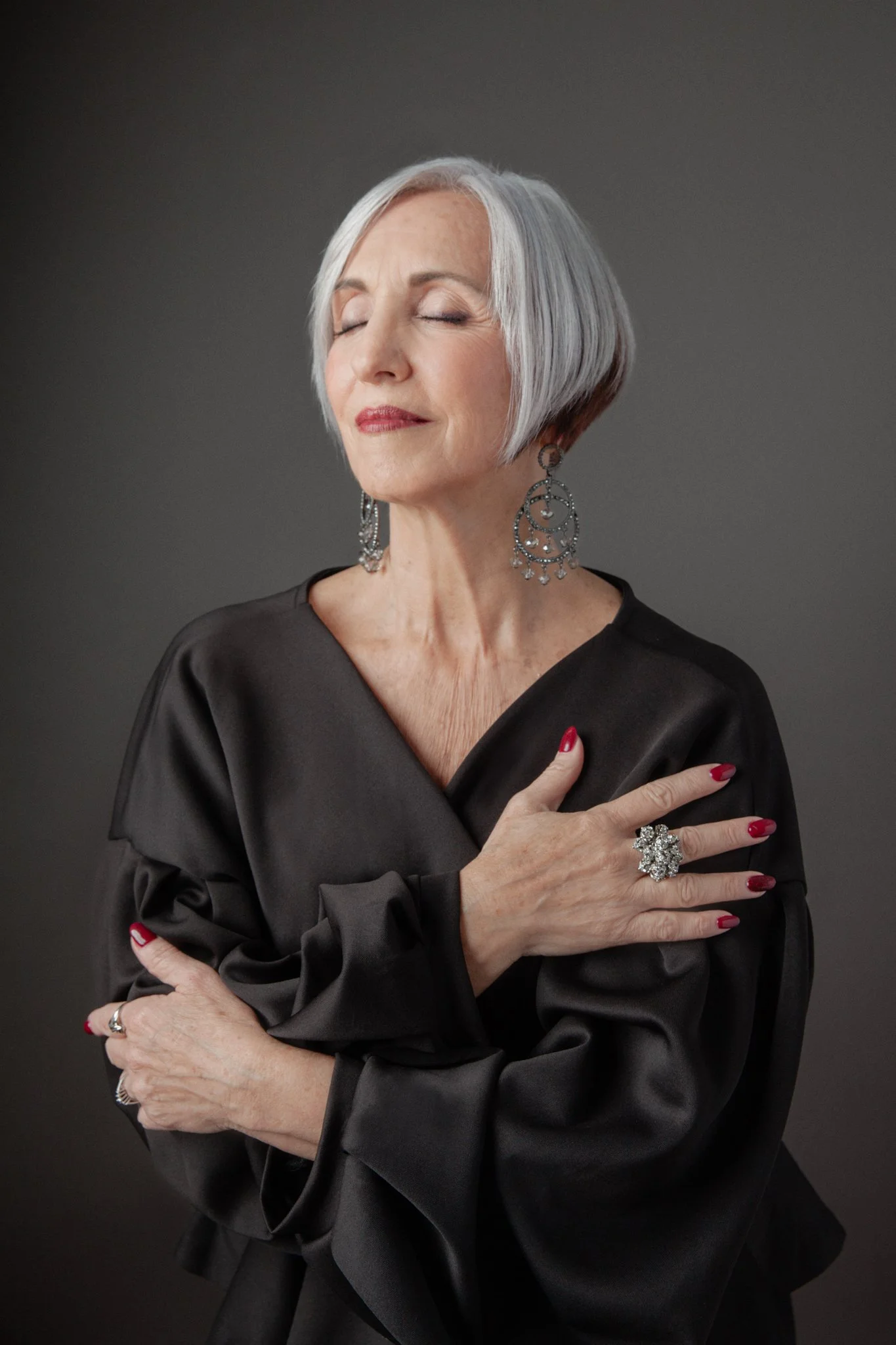 Elegant portrait of a silver-haired woman in a black satin blouse, during a studio portrait session in Pensacola.