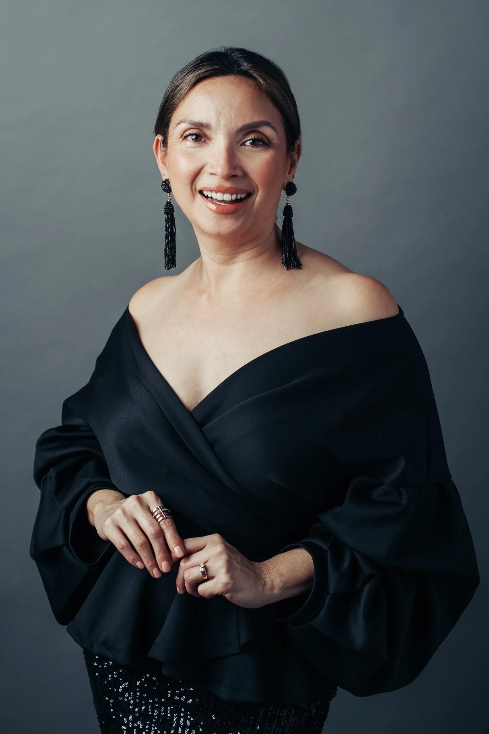 Portrait photographer Tamara Ibanez smiling in a black off-the -shoulder blouse.