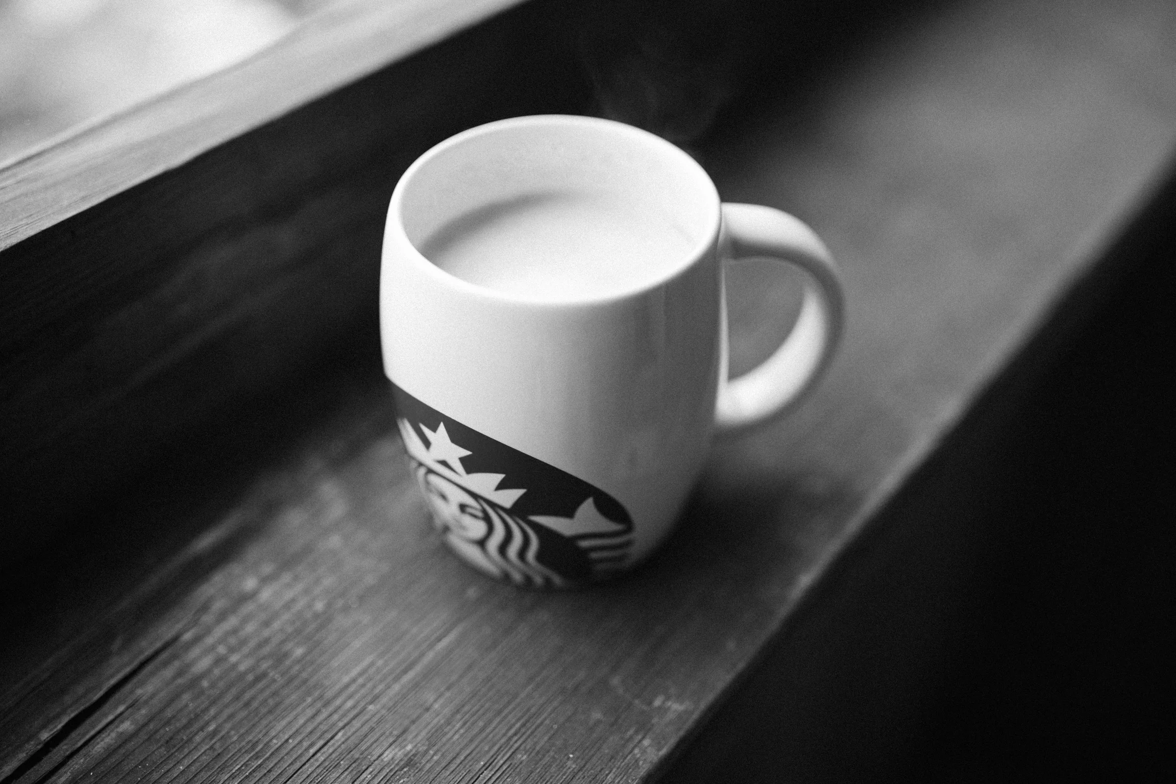 A mug of coffee on a wooden windowsill, with the Starbucks logo