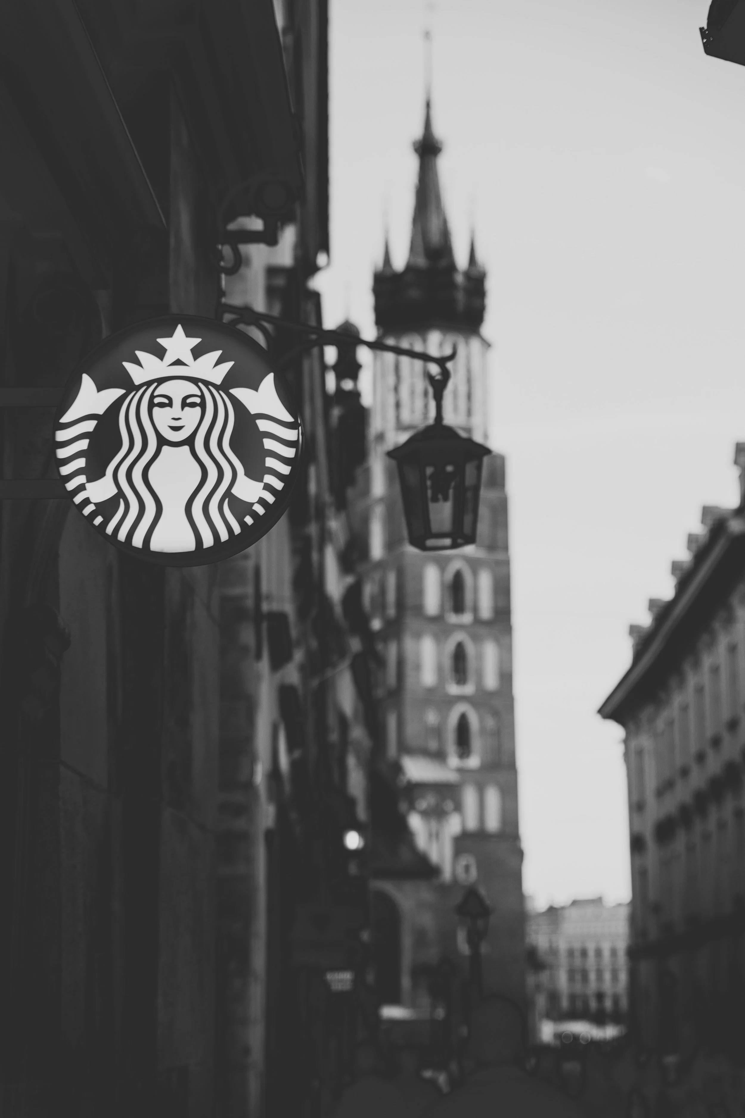 A Starbucks sign hangs in the foreground, with a city street scene behind