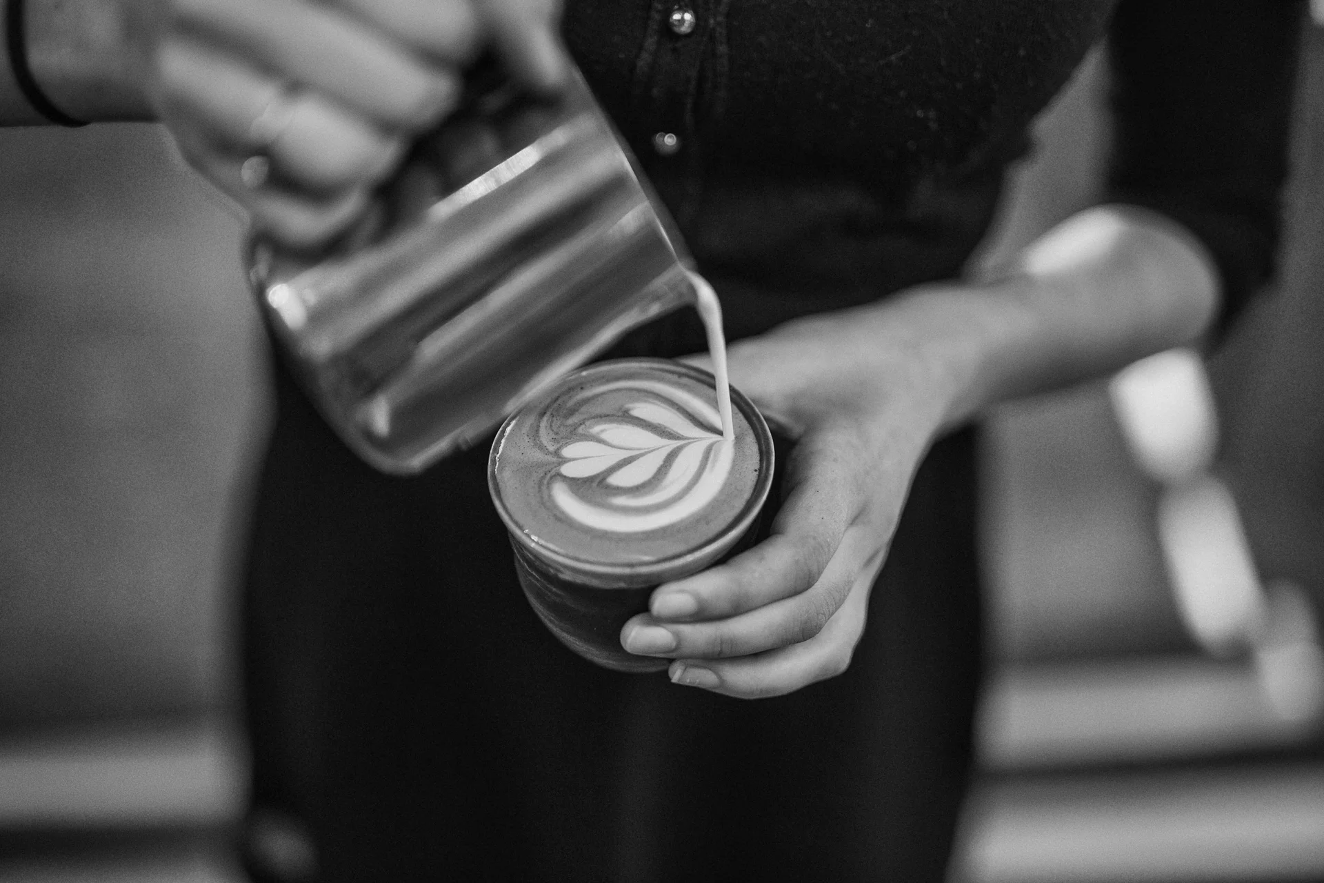 A barista pouring latte art, seen from above