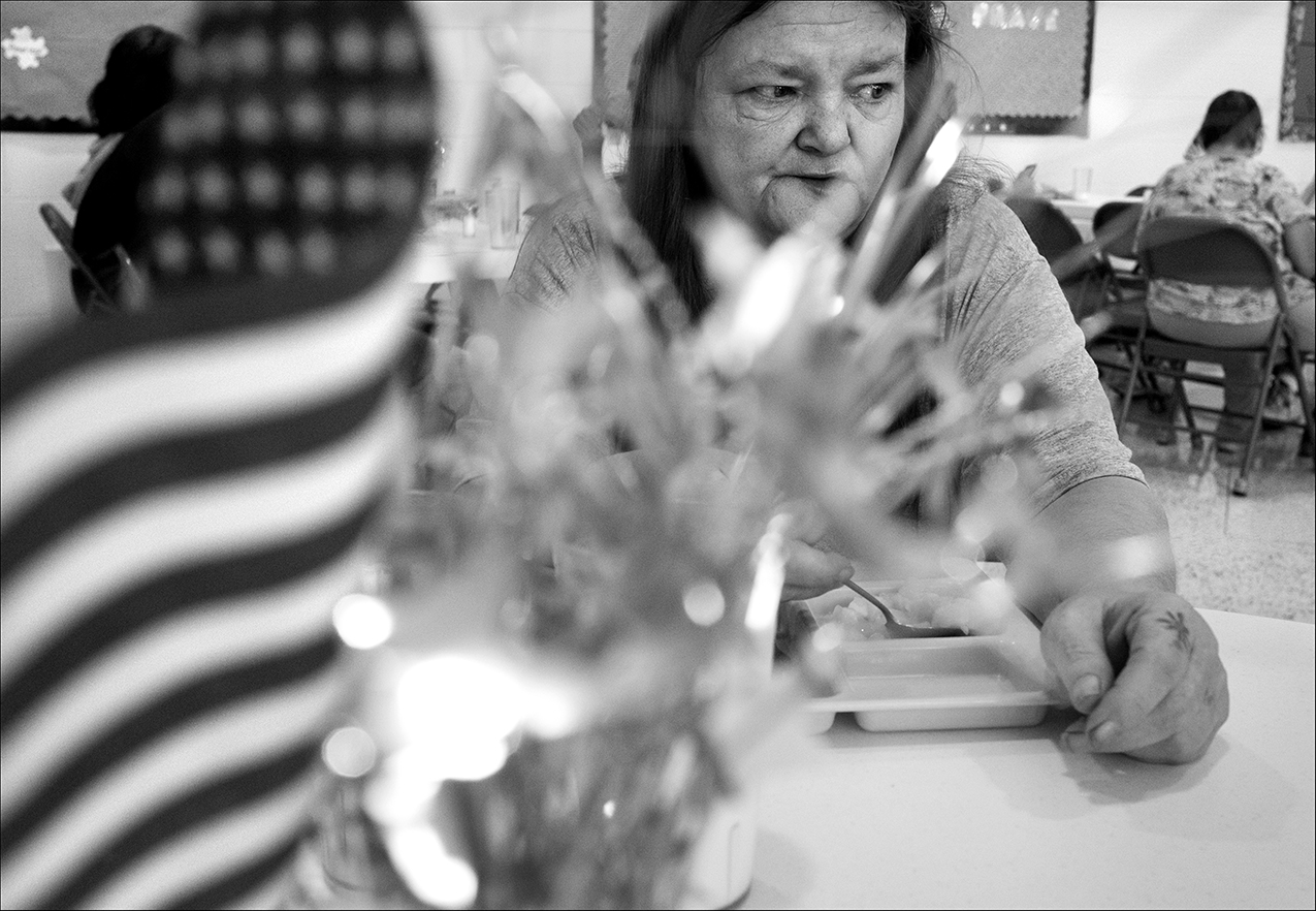 July 2017: Standing to alleviate her chronic back pain, Brenda eats a free meal at Salem Church, which provides meals to those in need each Saturday afternoon. Brenda learned in October 2017 that she needed a hip replacement, which is scheduled for January 2018