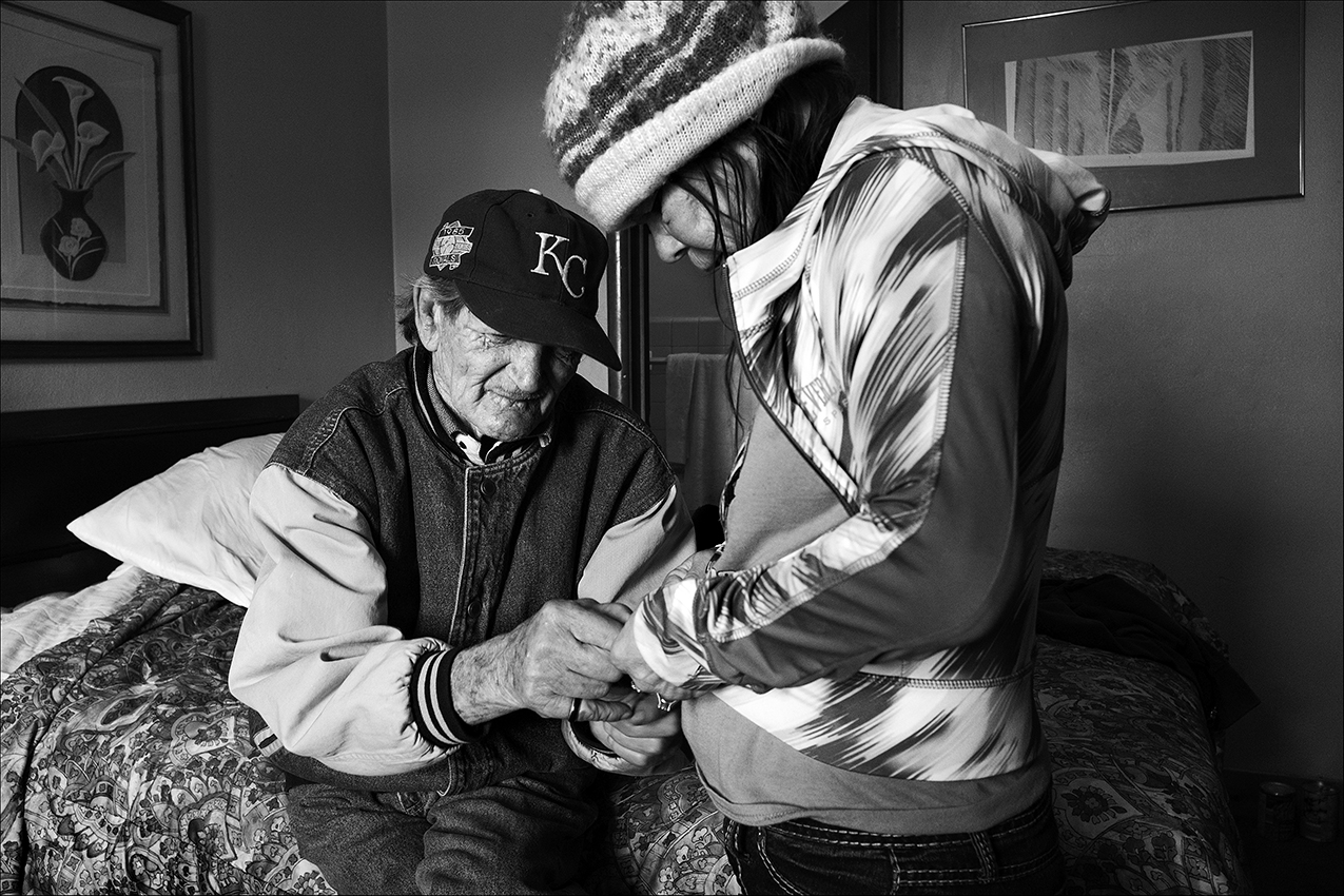 March 2017: Clarence zips up a jacket he bought for Vickie at a thrift store. Although Clarence owns only two pairs of pants and a couple of shirts, he occasionally buys Vickie nice but inexpensive clothing, toiletries, or other necessities for her out of his monthly retirement check. Many needed items are still out of reach. When Vickie’s purse was stolen with her glasses inside, she had to wait 11 months for replacement glasses.