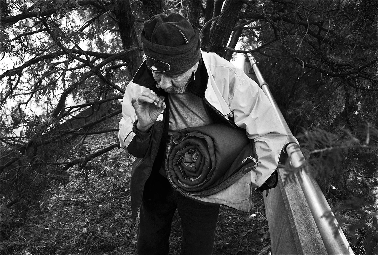 April 2017: James finishes a cigar early one morning after sleeping in a cedar grove next to the History Museum. “Man, it was cold last night. I ain’t used to this shit.” A few days later, police officers told him he had to leave. “They were nice about it but now I have to find a new place to stay.” 