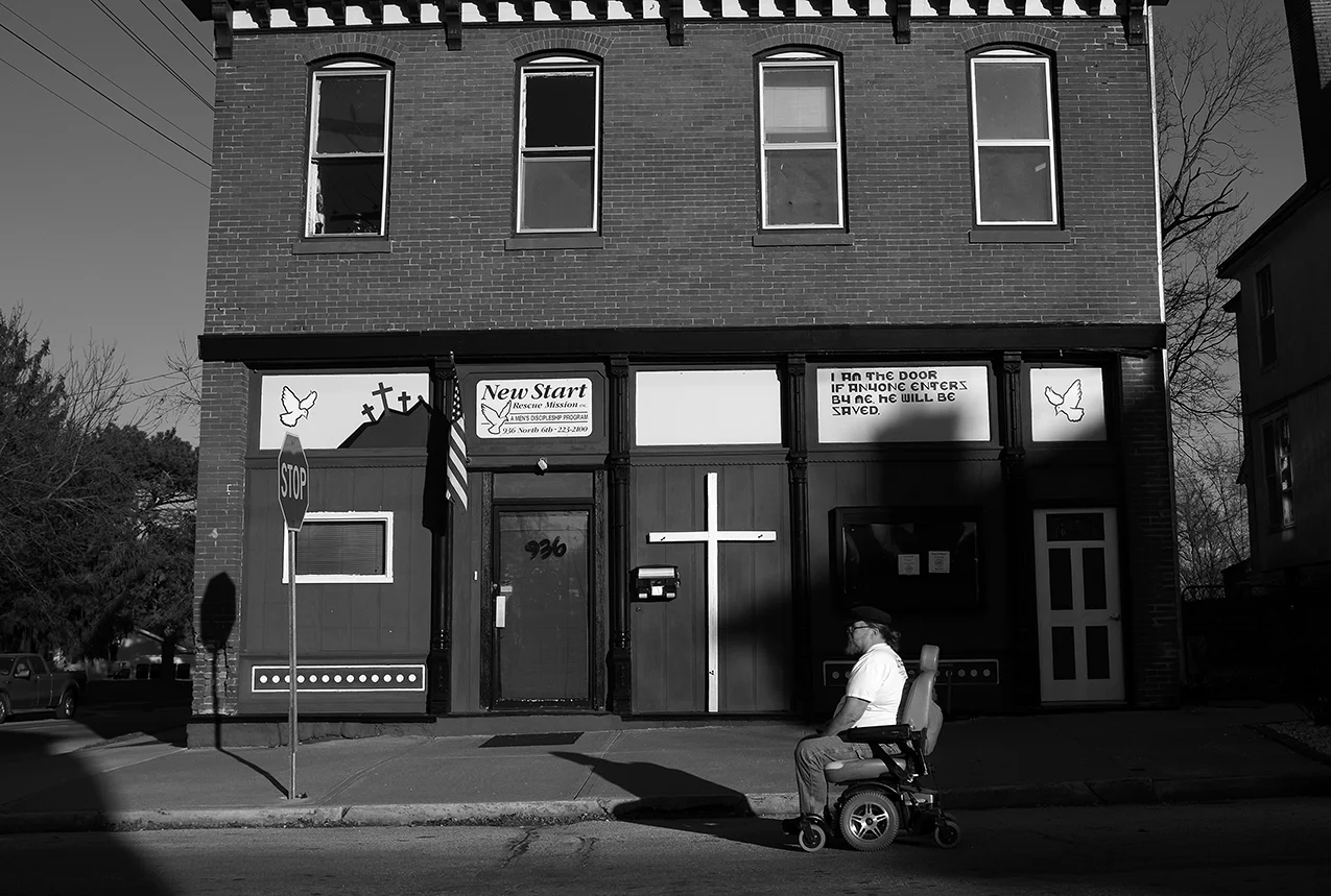 February 2017: Mark maneuvers his wheelchair on the street to avoid sidewalks in disrepair. “I’m currently in a handicap accessible apartment which is ideal for my wheelchair and me. But, I also need to get to meetings, to get to the soup kitchen, and I need to get to the pantries, and that requires me to go out with my chair, which in itself has been an issue. I've had to have two complete sets of tires on my wheelchair replaced. The chair is just like a car to me. It cost me just about what a car would cost except for I don't have gas I got electricity. That in itself is 80 to 120 dollars a month.” Mark says maneuvering some of the Quincy sidewalks isn’t ideal. “They got potholes on the sidewalks that if you hit one of them with these tires it's gonna break 'em. I can't get around without causing damage to my chair. Without this chair, I couldn't do none of what I do.” Mark talks about wheelchair inaccessibility issues. “It’s demeaning, you know? I’m close to uptown and I like to shop. I don’t necessarily like to buy things but I like to keep track of trends. I can’t even get in the store to see what they got. There’s a lot of buildings I would like to get into but can’t.”