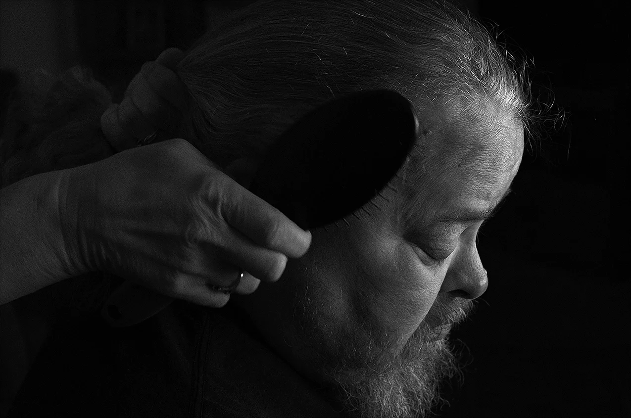 February 2017: After a morning shower Mark’s personal assistant brushes his hair. Mark relies greatly on his personal assistant to help him with the basics of getting in and out of bed, and in and out of his wheelchair. When Mark’s washing machine broke, he couldn’t afford to purchase another, so his personal assistant began bringing his clothes home to wash along with the household laundry she does for her family of five. “Well, I have a PA that came with me from the nursing home. She makes sure my bills get paid, she does my shopping and now that my washing machine has broken down she takes my laundry home and does it.”
