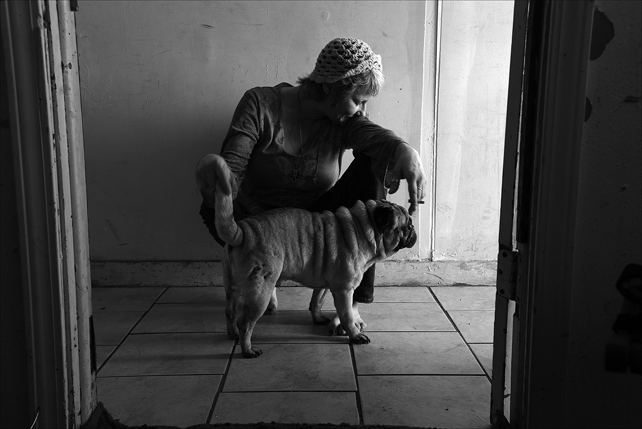 February 2017: Trish sits with her dog in the apartment she lived in before being evicted. By spring she will be homeless, living in abandoned buildings, while trying to find a job. 