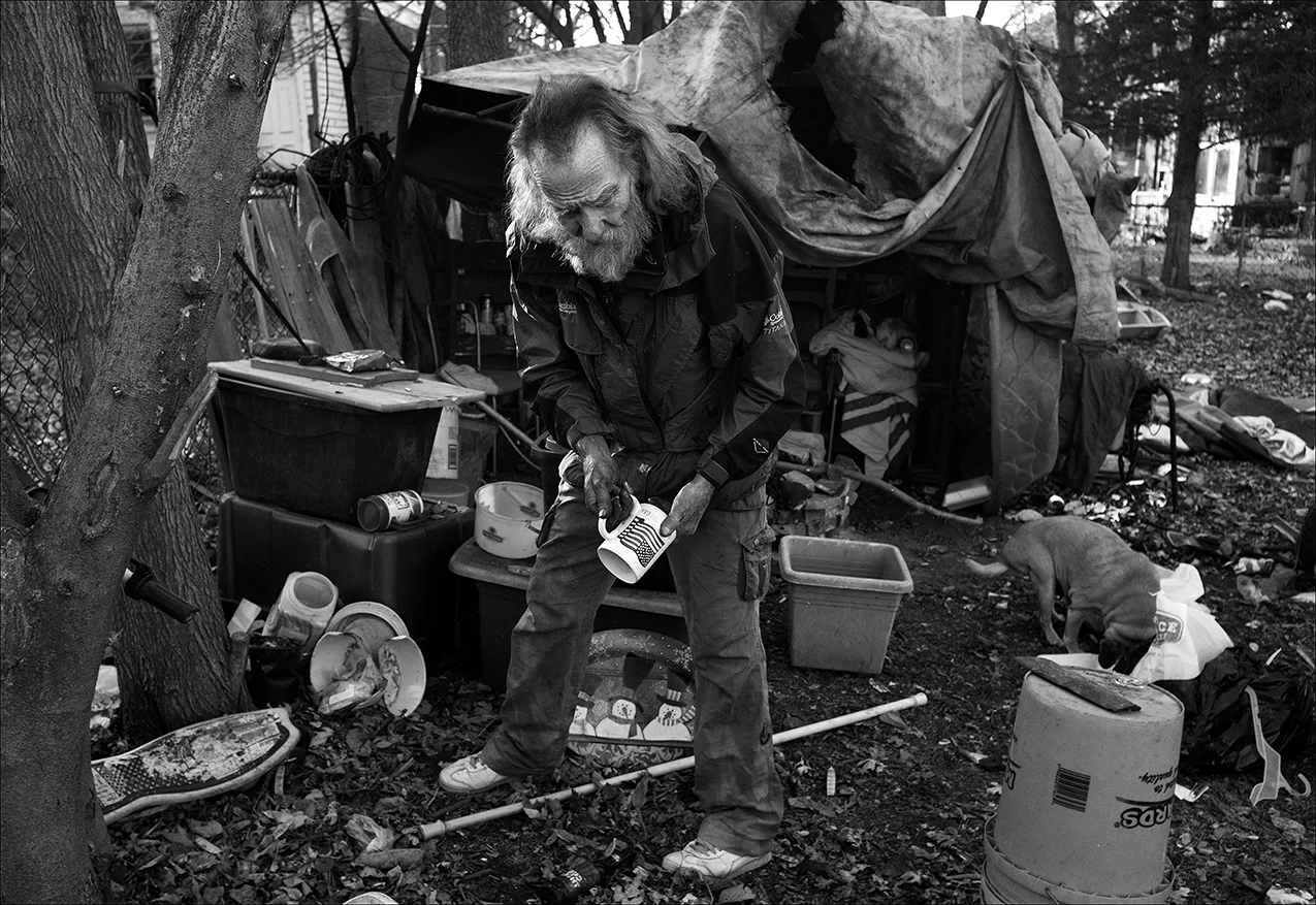 December 2017: On a cold December day, Walter organizes a living area in his homemade shelter made of mattresses, tarps and a plastic swimming pool. The utilities meter still has not been installed in the house he rented back in July. The house remains without heat and water pipes have frozen. Walter says the homeowner told him, on a handshake, she would do a rent-to-own agreement with him, but that the landlady’s son is harassing him. “Well, I’ve been living in my back yard. At first, I was just around a fire pit sitting in a chair but since it’s got cold and it’s going into December it’s getting cold out there. I get kind of smudgy (from the fire soot) but it helps out. The way you deal with the smoke is you sit down and let it go over your head. I can heat water over the fire pit and wash off, but it’s not like being in a house with a shower and all that, and most people wouldn’t know. The landlady’s son jerked the meter out and evidently he messed up the meter box while he was taking it out because the power company will not turn it on with the meter box in the shape it’s in. It’s just got a small piece missing but that’ rules and regulations that we have to go by if we wanna live and do well. “I couldn’t get anybody to co-sign for me so I could buy a house with a regular mortgage so I had to rent-to-own which is risky, as far as I’m concerned, but rent-to-own is the only option I’ve got. I pay $350 plus bills for the house and also have a washer and dryer I could be using now with electricity, but I pay $50 a month on that so it makes it $400 plus bills for the whole thing. I like the house and the yard. It needs a little work on it but I know I’ll do that. It takes time and a little material. But the location is the worst in Quincy. And there is a lot of thieving and drug-dealing and all that stuff going on right around me and in my yard. So it’s really not a place that most people would want to live.”