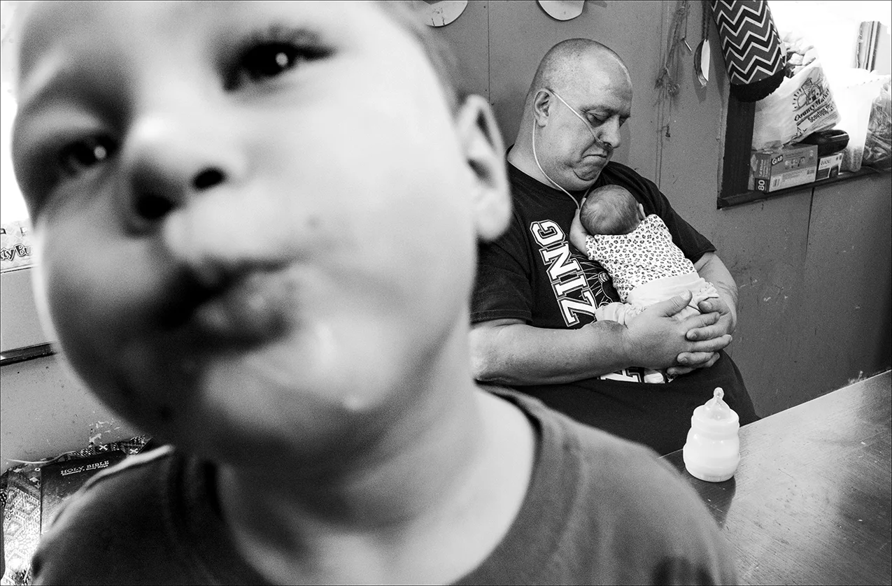February 2018: Chris cradles his new granddaughter, Madison Lou May, in his arms. Chris was told the cancer is spreading to other organs in his body and he has perhaps two or three months to live. Hospice arrangements have been made. Chris died within three weeks, on April 15, 2017 at age 57.