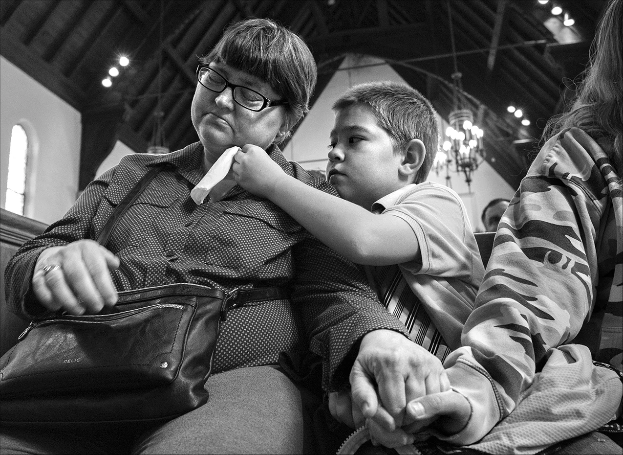 April 2018: Nicholas Weible, 10, offers his mother Wendy Smith a tissue during the memorial service for his father, Chris Weible, Friday, April 20, 2018, at First Christian Church in Quincy. The family, which struggles to make ends meet every month, learned from the Adams County coroner that Chris’ death certificate and ashes will be withheld until the family can reimburse the county $1000 for Chris’ cremation. Wendy lacks the $1000 demanded by the coroner and without the death certificate she fears she can’t have Chris’ social security benefits transferred to the children. The Adams County coroner says the State of Illinois is supposed to pay for the funerals of those who can’t afford them, but they haven’t been paying funeral homes for years, so the funeral homes are looking to the counties to pay for the funerals of indigent people. According to the coroner, if a person can’t pay for a loved one’s funeral, the county pays the funeral home $800 for handling the body and the county pays an additional $200 for the cost of the actual cremation. In an interview, the coroner said he has the survivors sign their rights of the deceased over to him. He then holds the ashes for up to six months. Those who can’t afford to reimburse the county the $1000 within that time are told they won’t be notified of where the ashes will be placed, other than the ashes will be placed in a cemetery of the coroner’s choosing. Wendy said that she was told by the coroner that she needed to sign a paper agreeing to pay $1,000 before getting Chris’ death certificate and his ashes back. “And if we didn't come up with it, he would be buried anywhere in some cemetery and we'd never know where he's at,” Wendy said. “He was just blunt. You'll never know where they're at.”