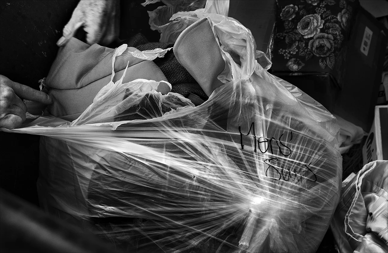 February 2017: Dennis fishes out this bag of men's suits from the dumpster behind a faith-based thrift store on Maine Street in Quincy. While Dennis and many others can't afford to buy clothes, or even afford to do laundry, it's common to find hundreds of items like brand-name, clean, new, and nearly new clothing and other items like luggage, shoes, and children's books in very good to excellent condition in the store's dumpsters on a regular basis.