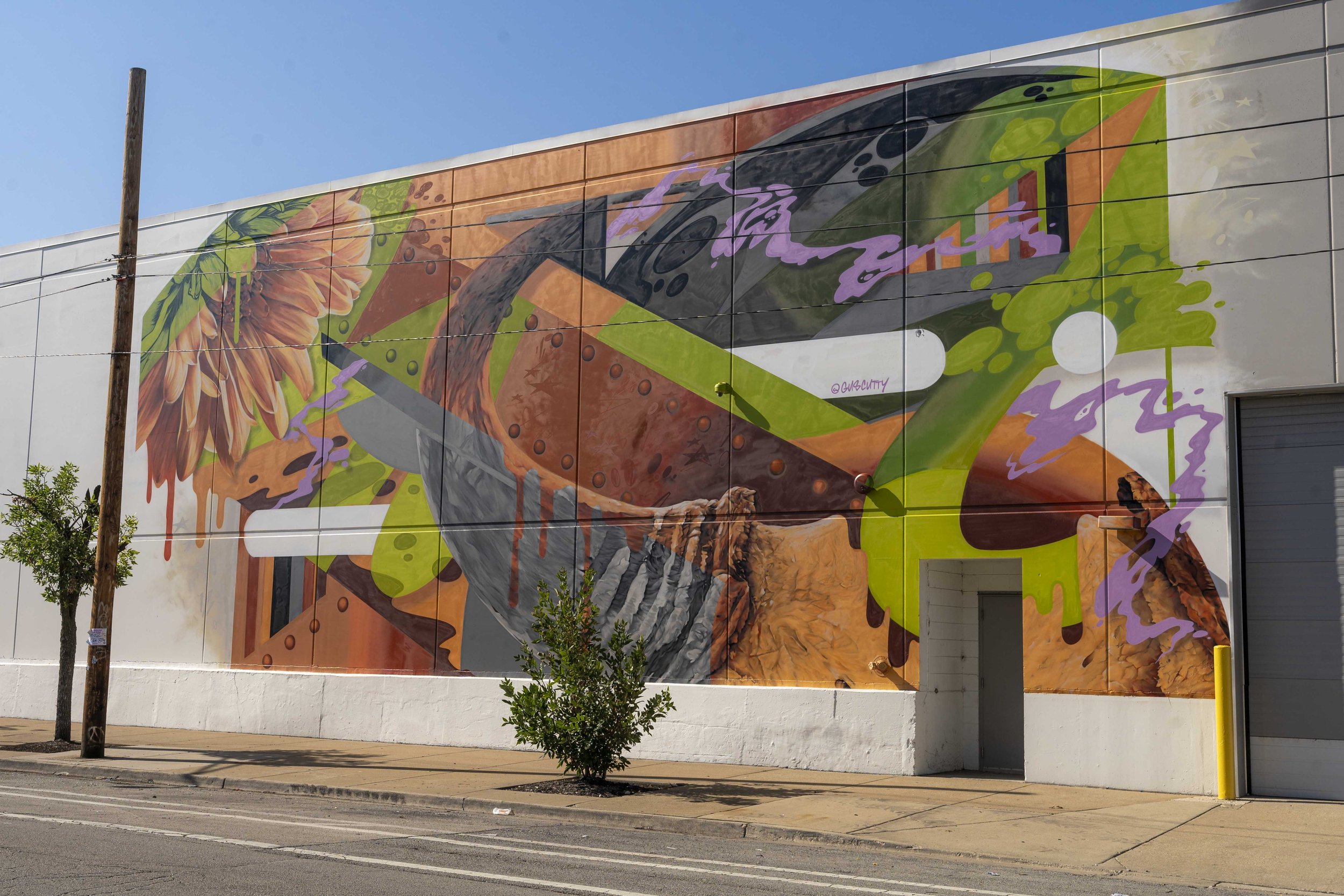 Colorful mural on a building wall featuring abstract shapes and a sunflower.