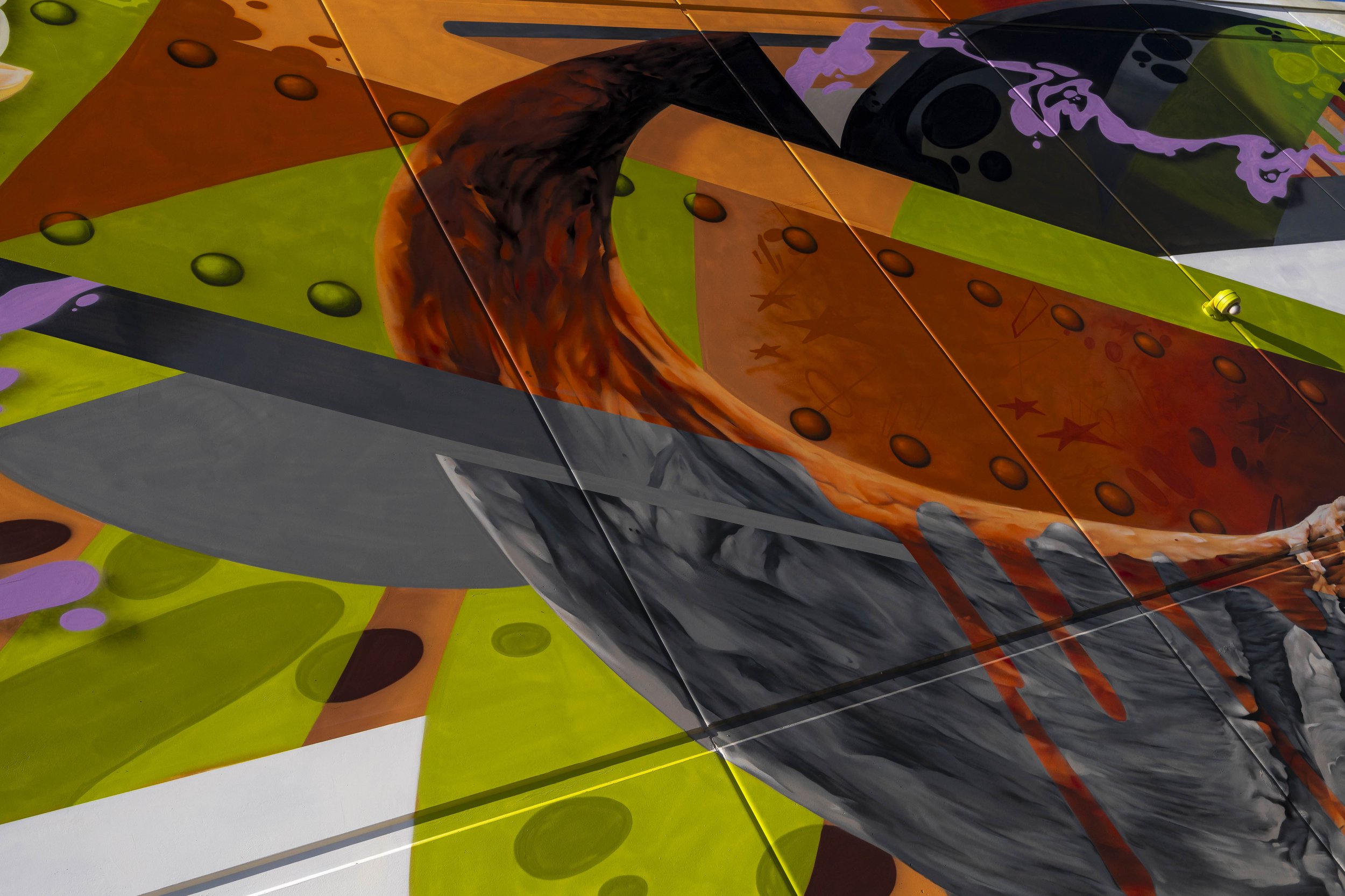 Abstract graffiti mural featuring vibrant colors including orange, green, and purple, with swirling shapes and lines.