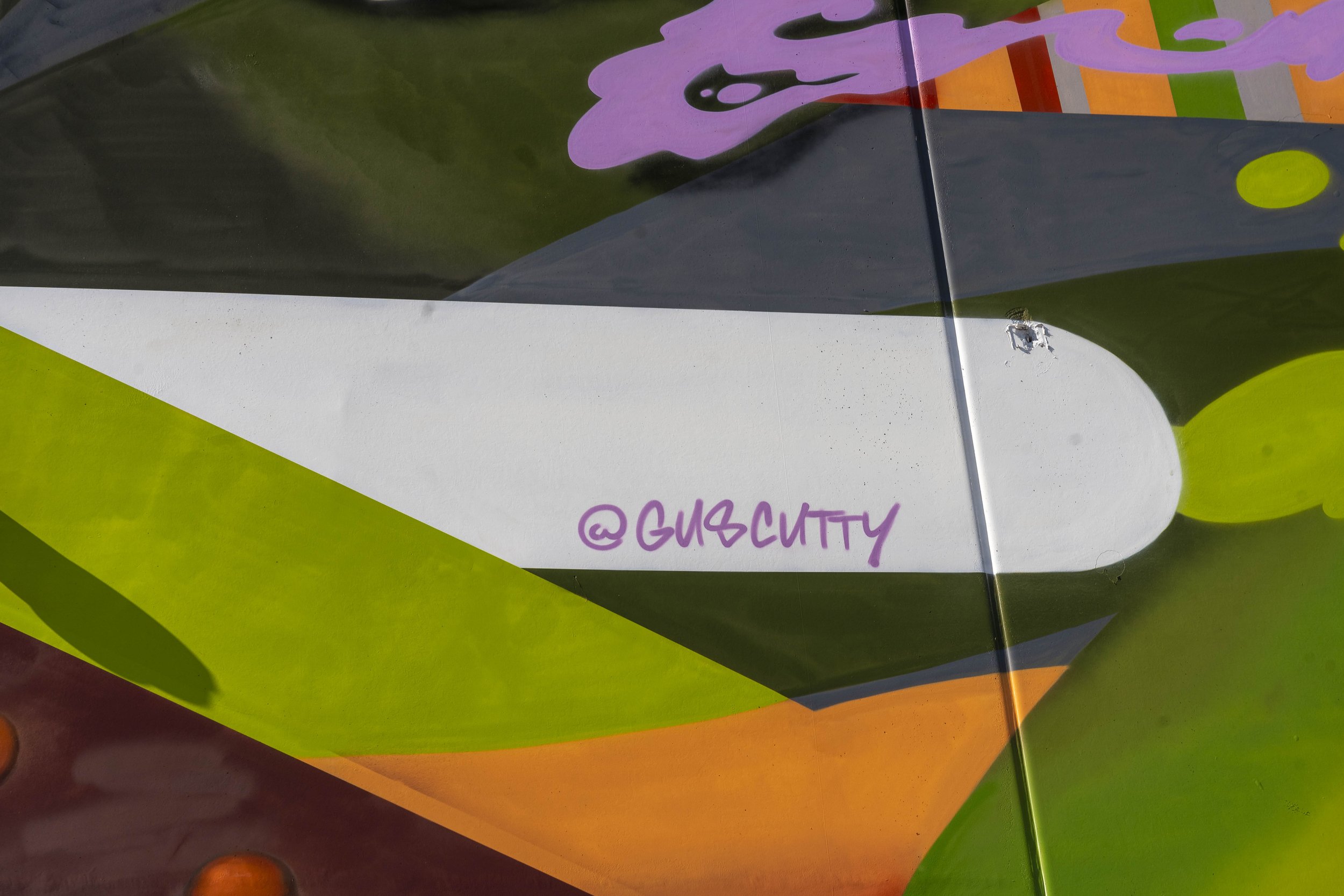 Colorful graffiti art with a social media handle @guscutty.
