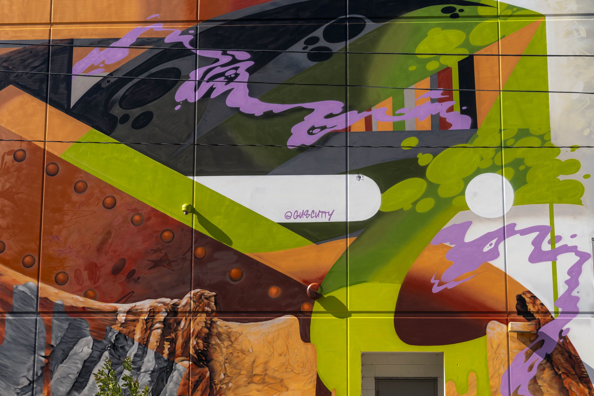 Colorful abstract mural with geometric shapes and vivid colors on a wall.