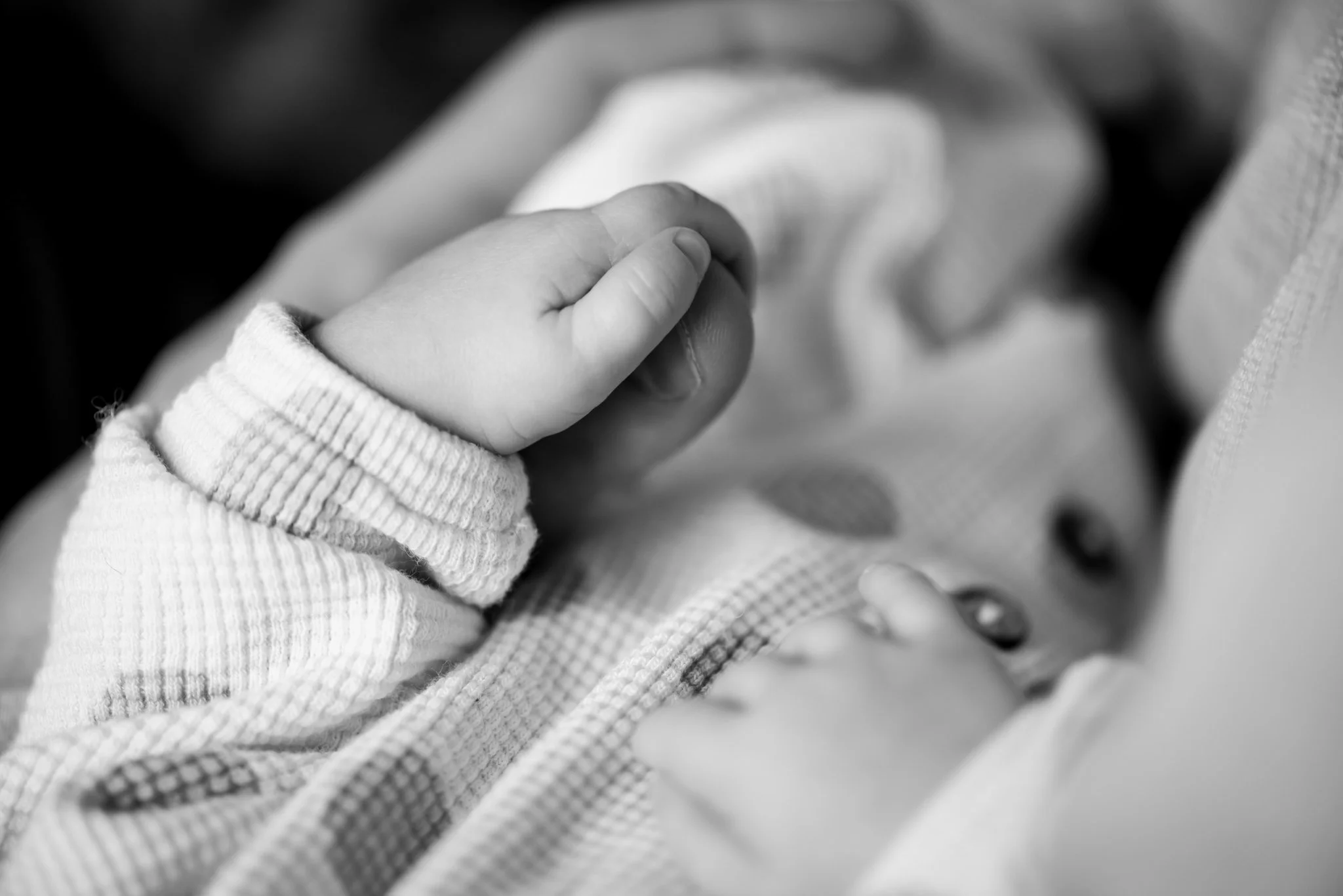 black and white photo of baby's tiny hand holding dad's thumb