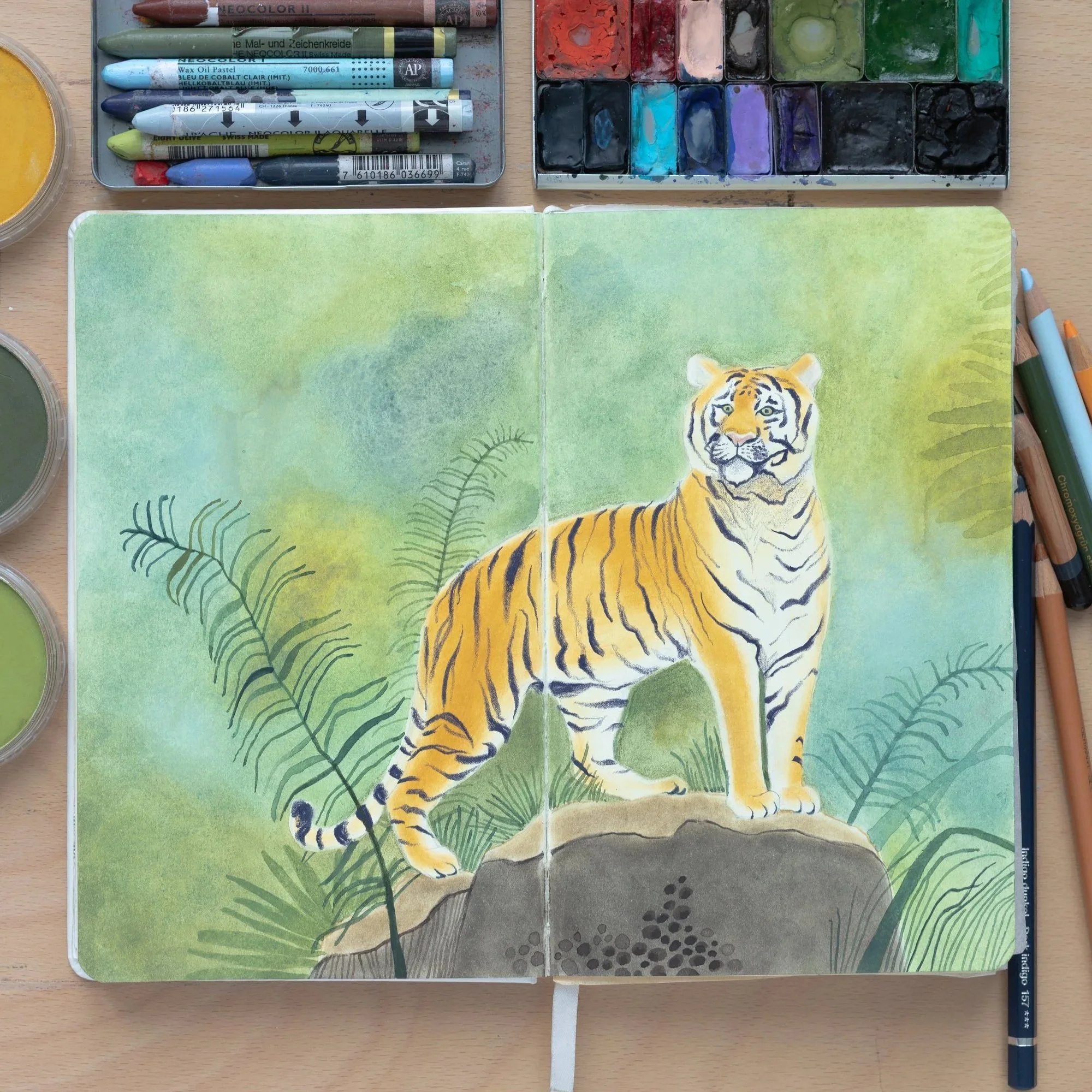 sketchbook ouvert entouré de matériels artistiques