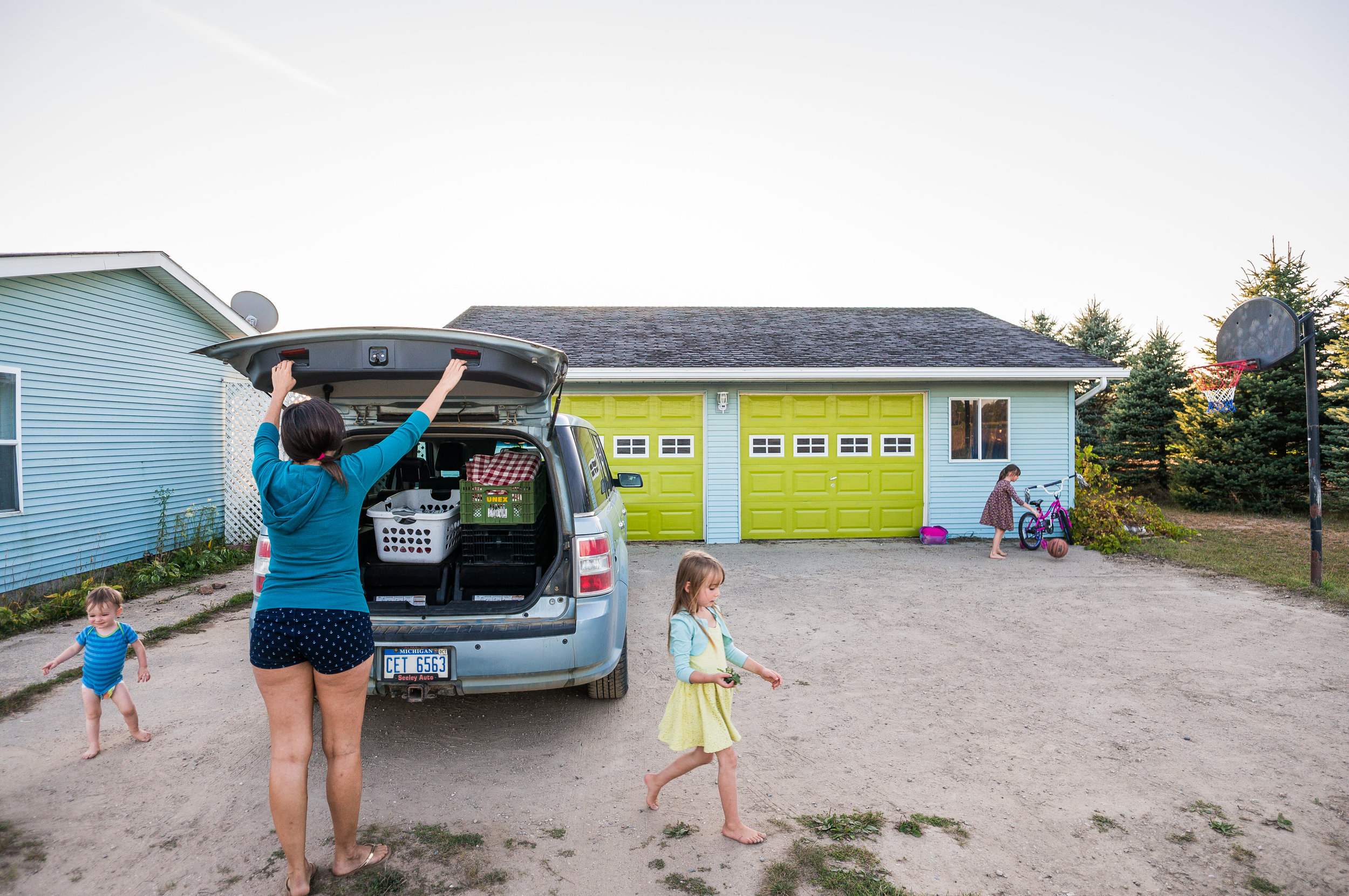  Michelle unpacks the car while her kids wander around the driveway, Sept. 18 at their home in Elwell. 'Little T', left, often wanders towards the road, requiring constant supervision from his parents or siblings.&nbsp; 