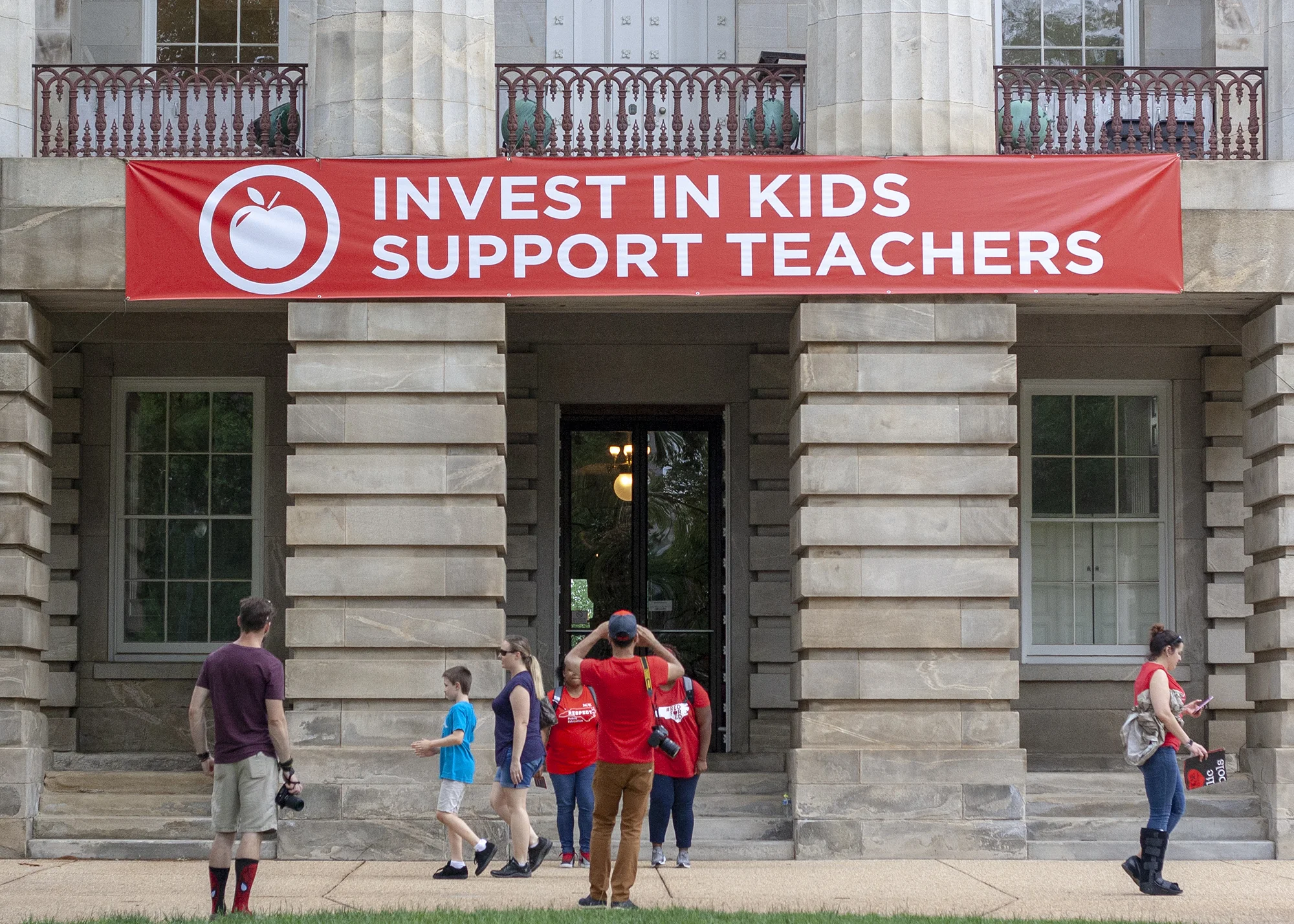 Attendees leaving the Rally for Respect photograph a banner on the North Carolina State Capitol.