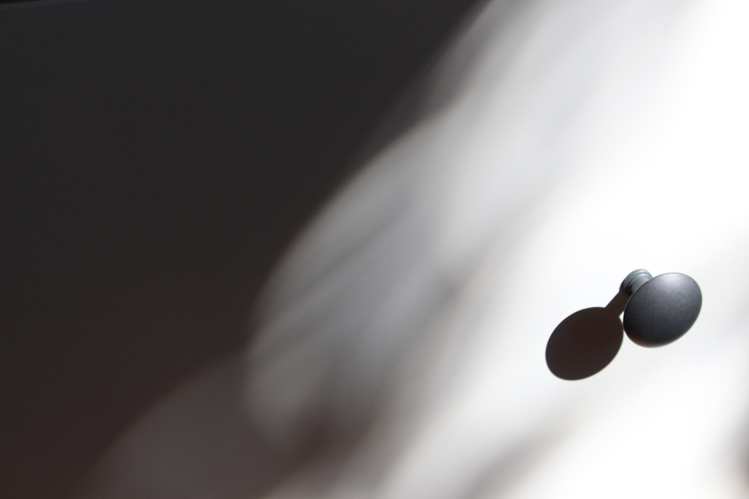 White surface and black door knob in heavy shadow.
